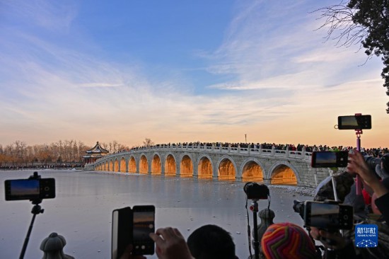 12月22日，游客在颐和园拍摄“金光穿洞”景象。