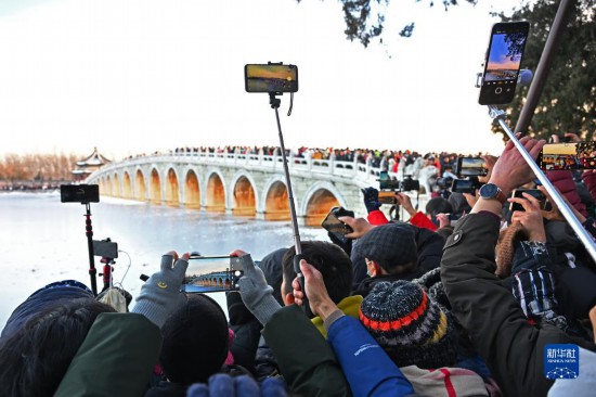 12月22日，游客在颐和园拍摄“金光穿洞”景象。