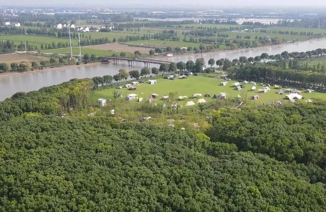 在上海松江区一处营地，市民游客在河边草地上搭起帐篷。（2023年9月29日，无人机照片）。新华社记者 方喆摄